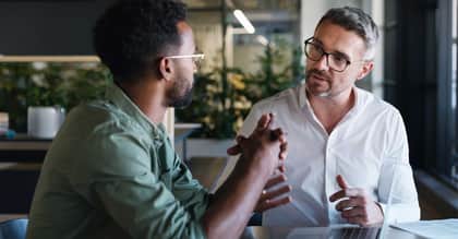 Two men discussing ideas at a table in an office space